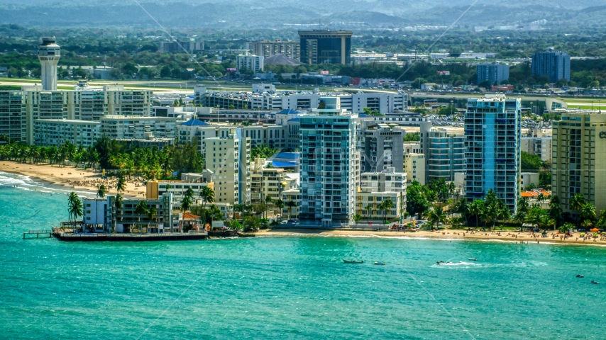 Apartment buildings on the coast by blue Caribbean waters, Carolina, Puerto Rico  Aerial Stock Photo AX102_008.0000153F | Axiom Images