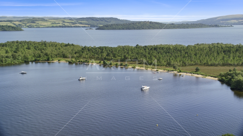 Boats along a small island beach, Loch Lomond, Scottish Highlands, Scotland Aerial Stock Photo AX110_109.0000158F | Axiom Images