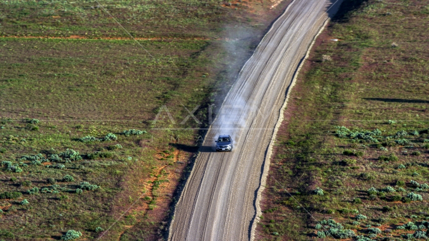 Silver SUV trailing a plume of dust on a desert road, Moab, Utah Aerial Stock Photo AX138_223.0000115 | Axiom Images