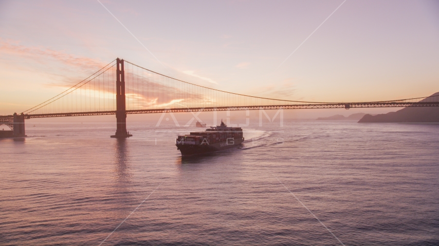 A cargo ship sailing by the Golden Gate Bridge, San Francisco, California, twilight Aerial Stock Photo DCSF10_041.0000043 | Axiom Images