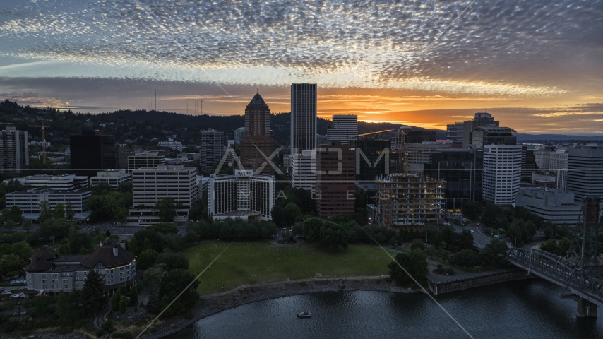 Skyscrapers behind hotel and office building near the river at sunset in Downtown Portland, Oregon Aerial Stock Photo DXP001_014_0008 | Axiom Images