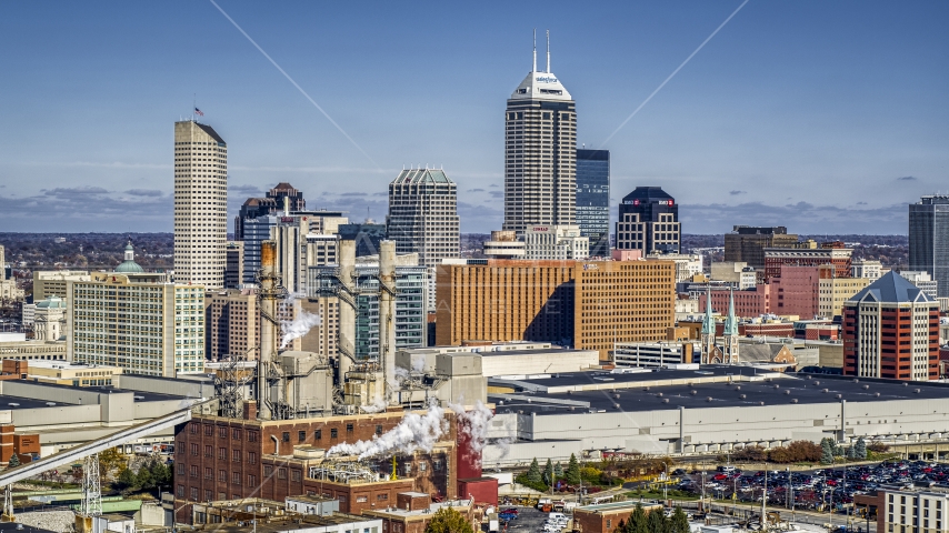 A factory with smoke stacks and the city's skyline in Downtown Indianapolis, Indiana Aerial Stock Photo DXP001_089_0008 | Axiom Images