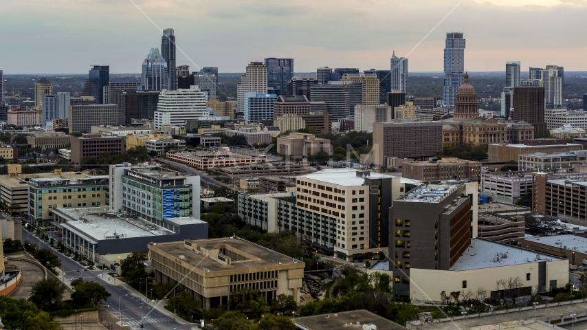 A hospital in the foreground, with skyscrapers and capitol dome in distance at sunset in Downtown Austin, Texas Aerial Stock Photo DXP002_105_0010 | Axiom Images