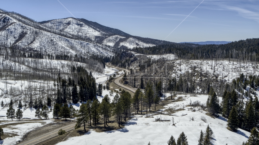 Winding road by snowy mountains and trees, New Mexico Aerial Stock Photo DXP002_134_0016 | Axiom Images