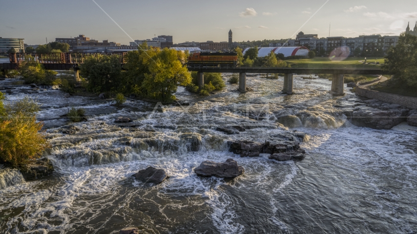 A train crossing bridge near waterfalls at sunset in Sioux Falls, South Dakota Aerial Stock Photo DXP002_176_0008 | Axiom Images