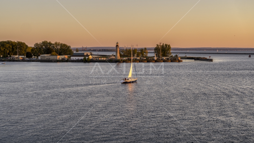 A sailboat on Lake Erie near a lighthouse at sunset, Buffalo, New York Aerial Stock Photo DXP002_204_0008 | Axiom Images