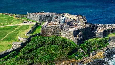 AX101_026.0000000F - Aerial stock photo of A historic fort and lighthouse beside blue waters, Old San Juan, Puerto Rico