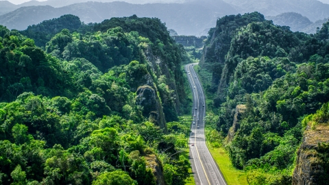 AX101_085.0000000F - Aerial stock photo of A highway cutting through lush green mountains, Karst Forest, Puerto Rico