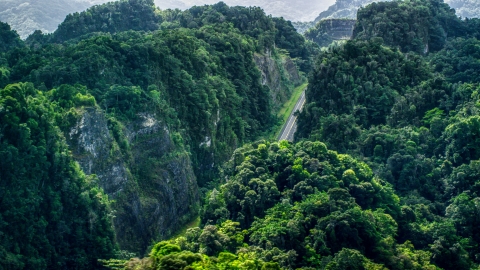 A highway cutting through lush green mountains, Karst Forest, Puerto Rico Aerial Stock Photos | AX101_086.0000000F