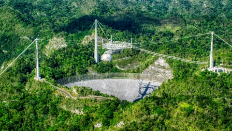 AX101_090.0000276F - Aerial stock photo of Wide shot of the Arecibo Observatory among lush green forests, Puerto Rico 