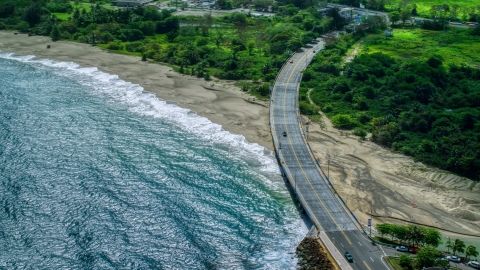 Coastal road cutting through trees and over a beach by blue water, Arecibo, Puerto Rico  Aerial Stock Photos | AX101_140.0000000F