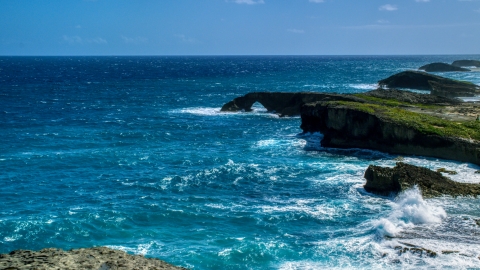 AX101_161.0000329F - Aerial stock photo of A rock arch in the blue water of a Caribbean island, Arecibo, Puerto Rico 