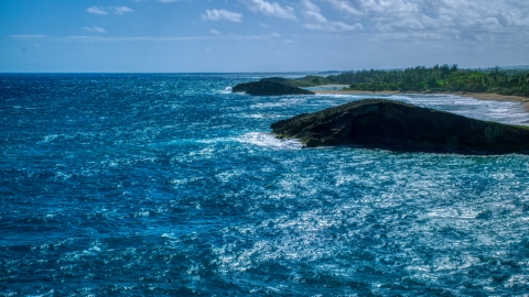 AX101_170.0000000F - Aerial stock photo of A pair of domed rock formations in crystal blue waters on the coast, Arecibo, Puerto Rico 