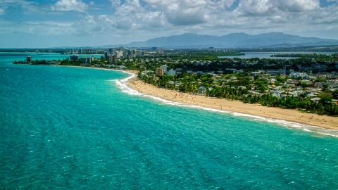 AX102_005.0000000F - Aerial stock photo of Beachfront homes beside beaches with tourists and crystal blue water, San Juan, Puerto Rico 