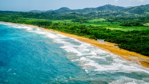 AX102_051.0000227F - Aerial stock photo of Ocean waves rolling toward an empty beach in Luquillo, Puerto Rico