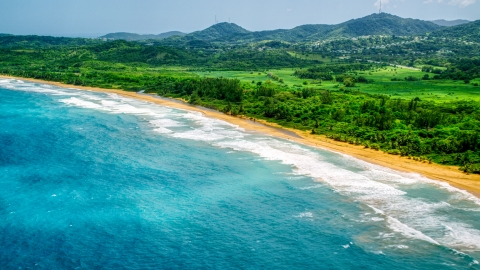 AX102_052.0000138F - Aerial stock photo of Waves rolling toward an empty beach and jungle in Luquillo, Puerto Rico 