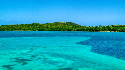 AX102_060.0000000F - Aerial stock photo of A view across crystal clear blue water of Cape San Juan Light, Puerto Rico