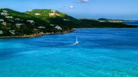 AX102_234.0000000F - Aerial stock photo of A sailboat near the Caribbean island coast with upscale homes, Southside, St Thomas 