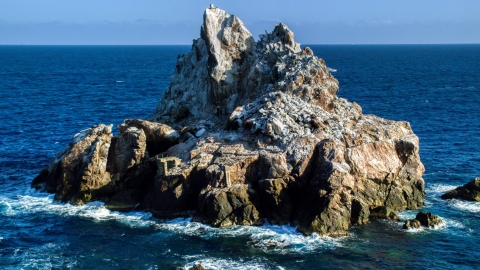 AX103_082.0000090F - Aerial stock photo of A jagged rock formation in Caribbean blue waters, St Thomas