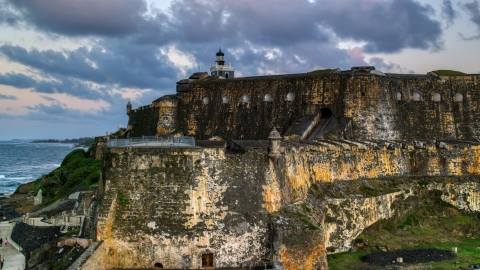 AX104_082.0000258F - Aerial stock photo of The walls of Fort San Felipe del Morro by Caribbean blue waters, Old San Juan, twilight