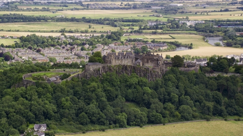 A view of hilltop Stirling Castle among trees, Scotland Aerial Stock Photos | AX109_019.0000084F