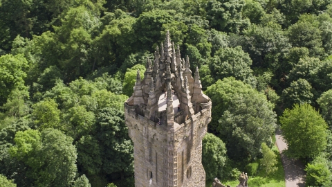 Top of iconic Wallace Monument near trees, Stirling, Scotland Aerial Stock Photos | AX109_052.0000110F