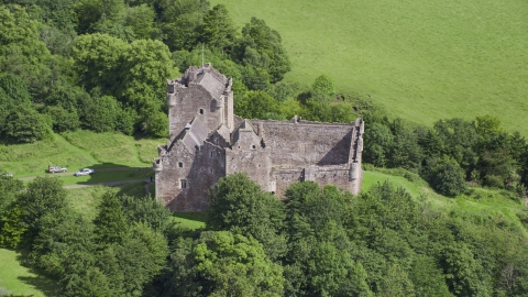 Iconic Doune Castle nestled in trees, Scotland Aerial Stock Photos | AX109_070.0000000F