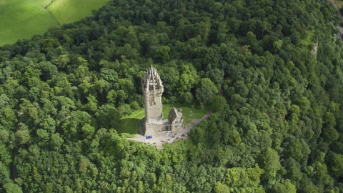 AX109_100.0000080F - Aerial stock photo of The iconic Wallace Monument surrounded by trees on Abbey Craig, Scotland