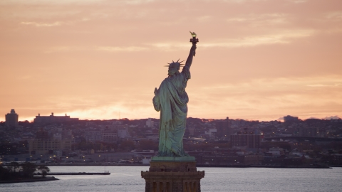 Statue of Liberty with a view of Brooklyn at sunrise, New York Aerial Stock Photos | AX118_042.0000000F