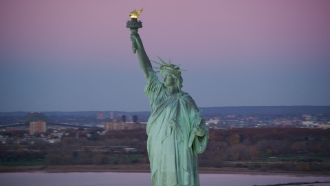 AX118_050.0000000F - Aerial stock photo of Statue of Liberty with purple sky at sunrise, New York