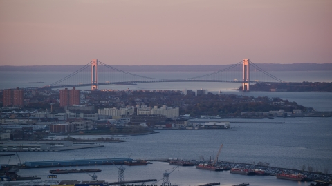 AX118_061.0000092F - Aerial stock photo of Verrazano-Narrows Bridge and waterfront apartment buildings at sunrise, New York City