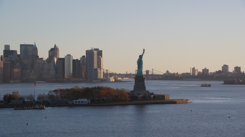 AX118_132.0000000F - Aerial stock photo of Statue of Liberty and Lower Manhattan skyscrapers at sunrise in New York City