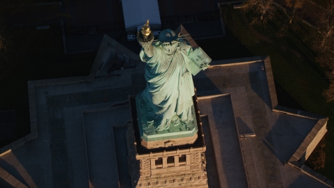 AX118_147.0000104F - Aerial stock photo of Bird's eye view of the Statue of Liberty at sunrise in New York