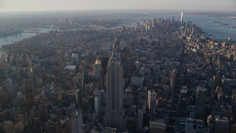 AX118_203.0000000F - Aerial stock photo of Empire State Building, the East River, and Lower Manhattan at sunrise in New York City