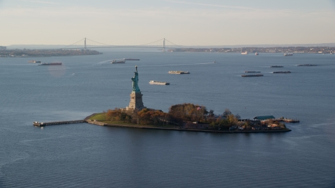 Statue of Liberty and barges in New York Bay at sunrise in New York Aerial Stock Photos | AX118_216.0000172F