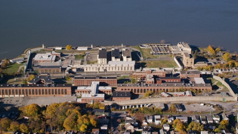 AX119_115.0000090F - Aerial stock photo of Sing Sing Prison beside the Hudson River in Autumn, Ossining, New York