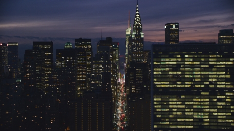 AX121_151.0000084F - Aerial stock photo of Midtown Manhattan city canyon by Chrysler Building and UN at night in New York City