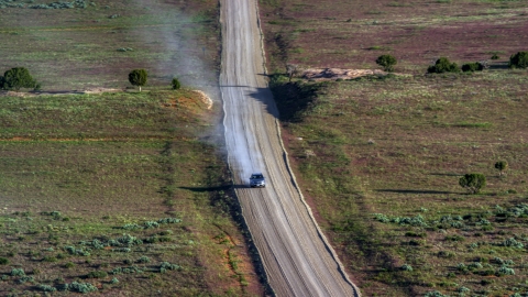 AX138_223.0000041 - Aerial stock photo of A silver SUV leaving a trail of dust on Hatch Point Road, Moab, Utah