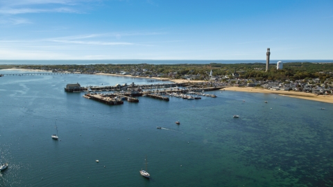 AX143_222.0000000 - Aerial stock photo of Boats docked at piers beside a small coastal town, Provincetown, Massachusetts