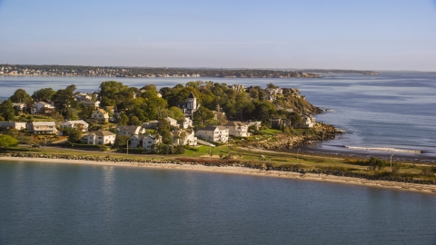 AX147_016.0000235 - Aerial stock photo of Coastal community nestled by trees on a peninsula in the bay, Nahant, Massachusetts