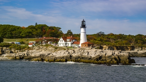 The Portland Head Light on a rocky shore, seen from the ocean in autumn, Cape Elizabeth, Maine Aerial Stock Photos | AX147_316.0000190