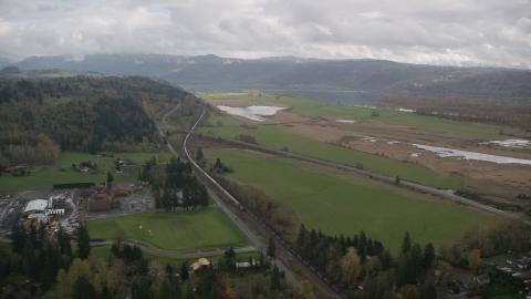 AX153_177.0000000F - Aerial stock photo of A train traveling by fields and country road in Washougal, Washington