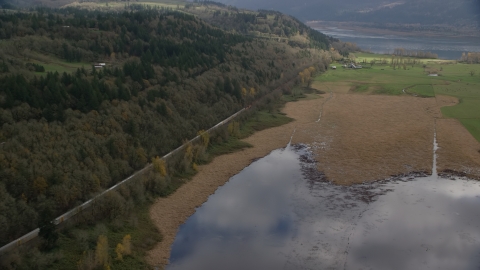 AX153_178.0000113F - Aerial stock photo of A train traveling by fields and water in Washougal, Washington