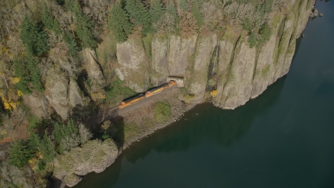 AX154_013.0000254F - Aerial stock photo of A train leaving Cape Horn Railroad Tunnel in Columbia River Gorge, Washington