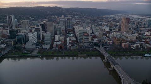 AX155_153.0000340F - Aerial stock photo of Downtown Portland skyscrapers and city park seen across the Willamette River at sunset