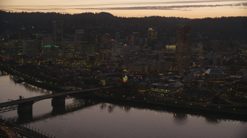 AX155_255.0000321F - Aerial stock photo of The Burnside Bridge over the Willamette River, White Stag Sign, US Bancorp Tower at sunset, Downtown Portland, Oregon