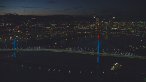 AX155_324.0000003F - Aerial stock photo of Tilikum Crossing and Marquam Bridge, with Downtown Portland skyline in the distance, Oregon, night