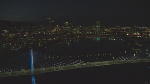 AX155_325.0000188F - Aerial stock photo of Tilikum Crossing and Marquam Bridge, with Downtown Portland skyline in the distance, Oregon, night