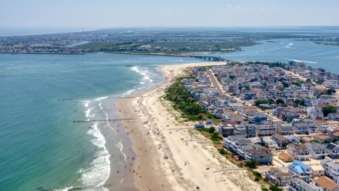 AXP071_000_0027F - Aerial stock photo of Beach goers by beachfront homes near Townsends Inlet Bridge in Sea Isle City, New Jersey