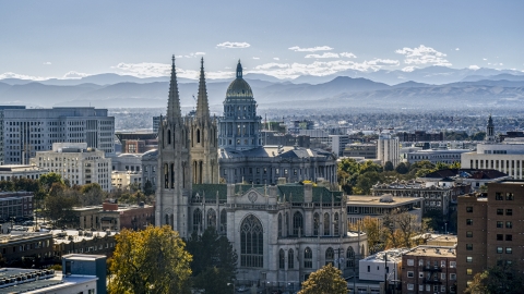 DXP001_000170 - Aerial stock photo of A cathedral and Colorado State Capitol dome with mountains in the distance, Downtown Denver, Colorado